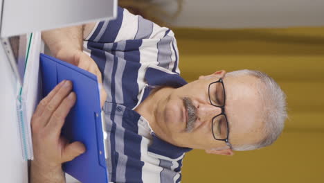Vertical-video-of-Home-office-worker-old-man-examining,-analyzing-documents.